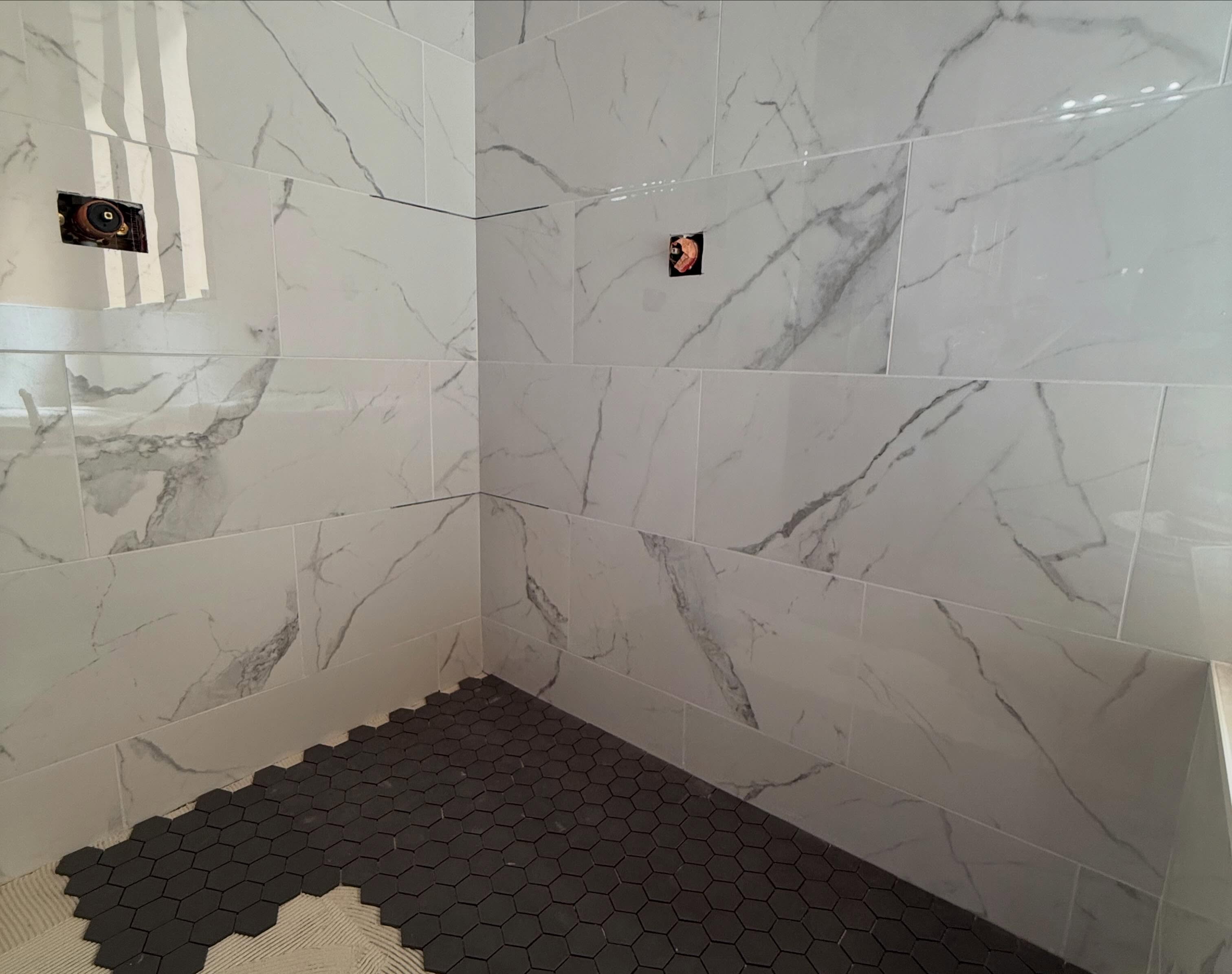 Calacatta marble wall tile with matte black hexagon shower pan
